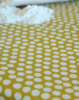 Close-up of oilcloth with white polka dots on a yellow background