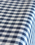 A close-up of a navy blue and white gingham checkered tablecloth draped over the corner of a table.