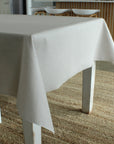 Grey tablecloth on a table with chairs in the background