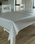 Dining table with a gray polka dot tablecloth in a room with chairs and decor.