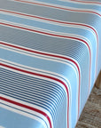 Close-up of a striped oilcloth with red, white, and blue lines on a light blue background.