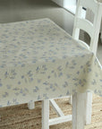 Floral-patterned tablecloth on a white table with a chair in a room setting.