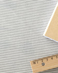 Striped oilcloth with a wooden ruler for scale on a white background