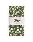 A folded green oilcloth with a white and black floral pattern, wrapped in a white paper band featuring a black horse logo and the text 'Swedish design since 1846'.