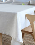 beige tablecloth on a wooden table with chairs in the background