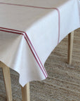 grain sack pattern tablecloth with red stripe on a wooden table
