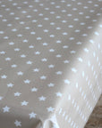 A close-up of a tablecloth with a repeating pattern of small white stars on a warm beige background.