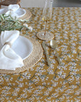 Table setting with floral tablecloth, plates, cutlery, and glasses.