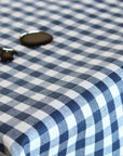 A close-up of a navy blue and white gingham checkered wipe clean tablecloth with balsamic vinegar spilled onto it.