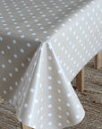 A light beige tablecloth with a white star pattern draped over a table, with wooden table legs and a woven rug visible underneath.