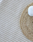 Close-up of a woven placemat with a candle on a striped tablecloth