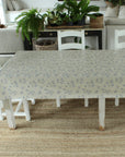 Table with floral tablecloth in a room with plants and furniture