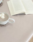 Cup of hot chocolate with marshmallows on a pink striped oilcloth next to an open book