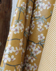 Mustard yellow oilcloth with floral pattern next to a striped oilcloth.