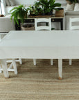 White dining table and chairs in a room with plants and furniture.
