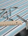 Metal tablecloth clips with a wooden ruler on a striped oilcloth