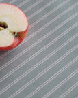 A close-up of a sliced red apple placed on a tablecloth with thin white vertical stripes.