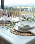 Elegant table setting with white plates, glasses, and napkins on a table with a scenic view.