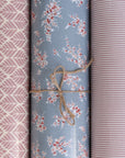 Three rolls of oilcloth with different patterns tied together on a neutral background