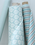 Three rolls of oilcloth with different patterns on a light blue background