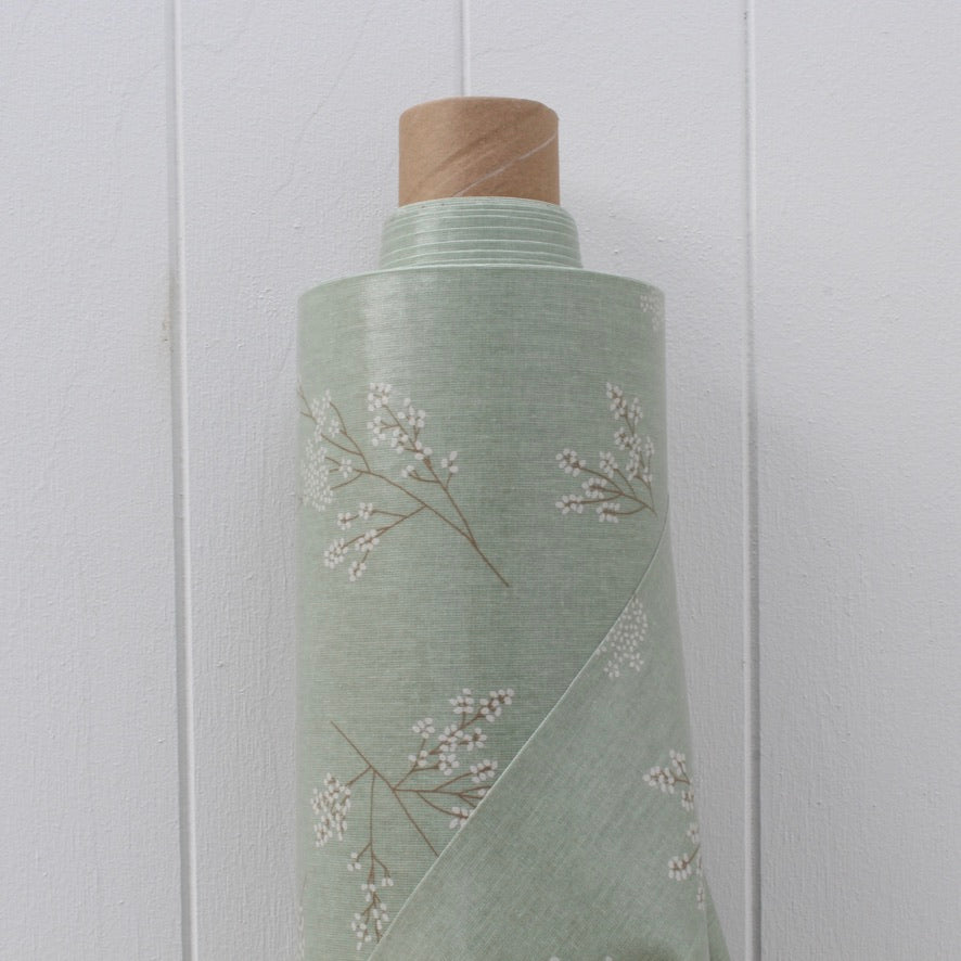 Roll of green oilcloth with floral pattern on a white background