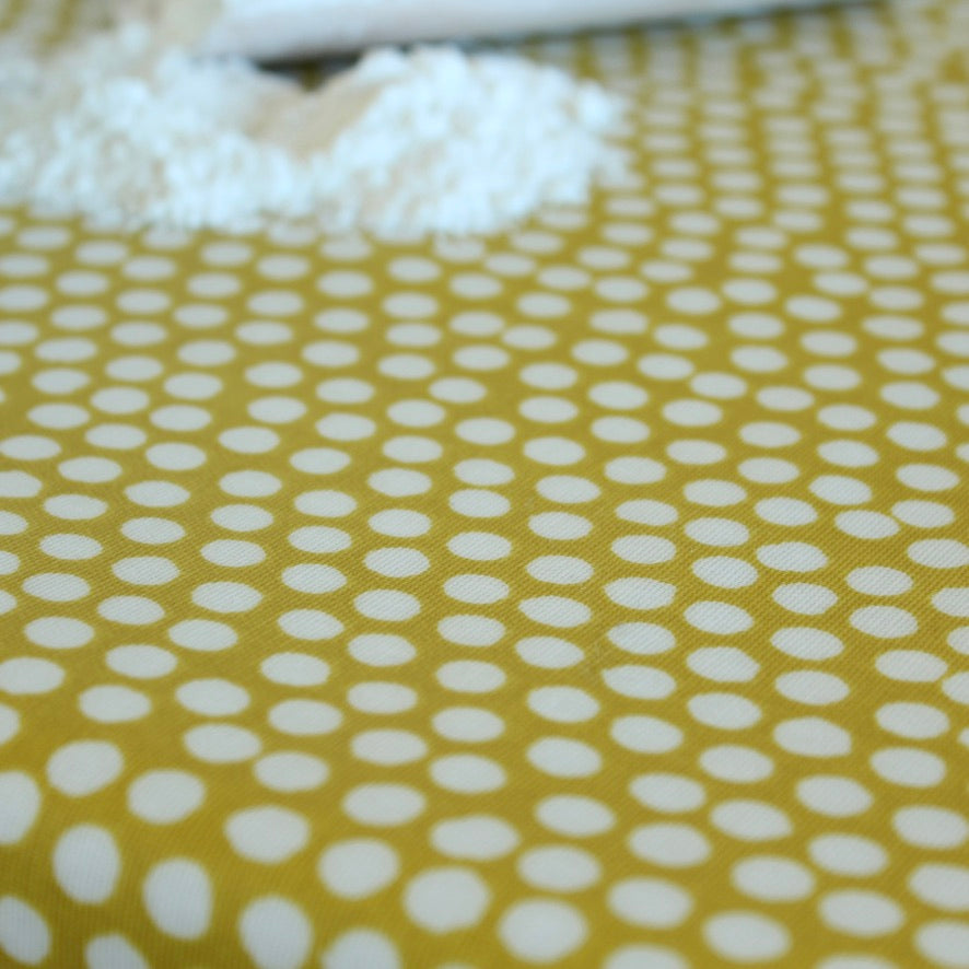 Close-up of oilcloth with white polka dots on a yellow background
