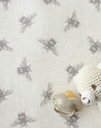 Baby pacifier and white knitted toy on an oilcloth with beige bee pattern.