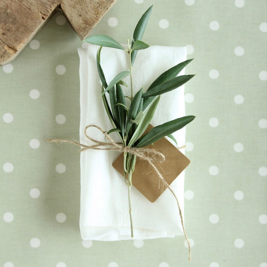 Bouquet of green leaves tied with twine on a white napkin on a polka dot oilcloth