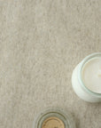 White candle in a glass jar on a beige oilcloth