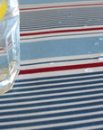 Clear glass bottle with a yellow cap on a striped oilcloth surface