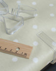Clear plastic tablecloth clips on a polka dot fabric surface with a wooden ruler for scale.