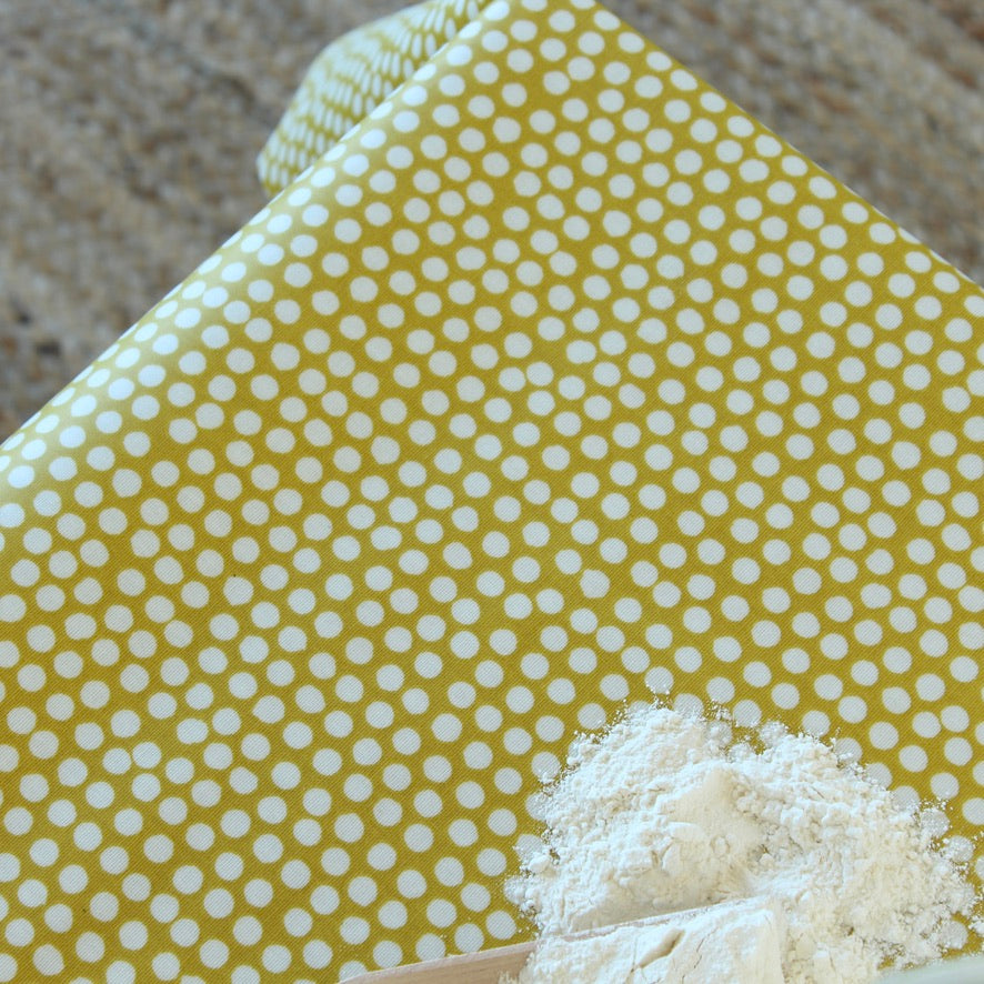 Yellow oilcloth with white polka dots and a small pile of flour