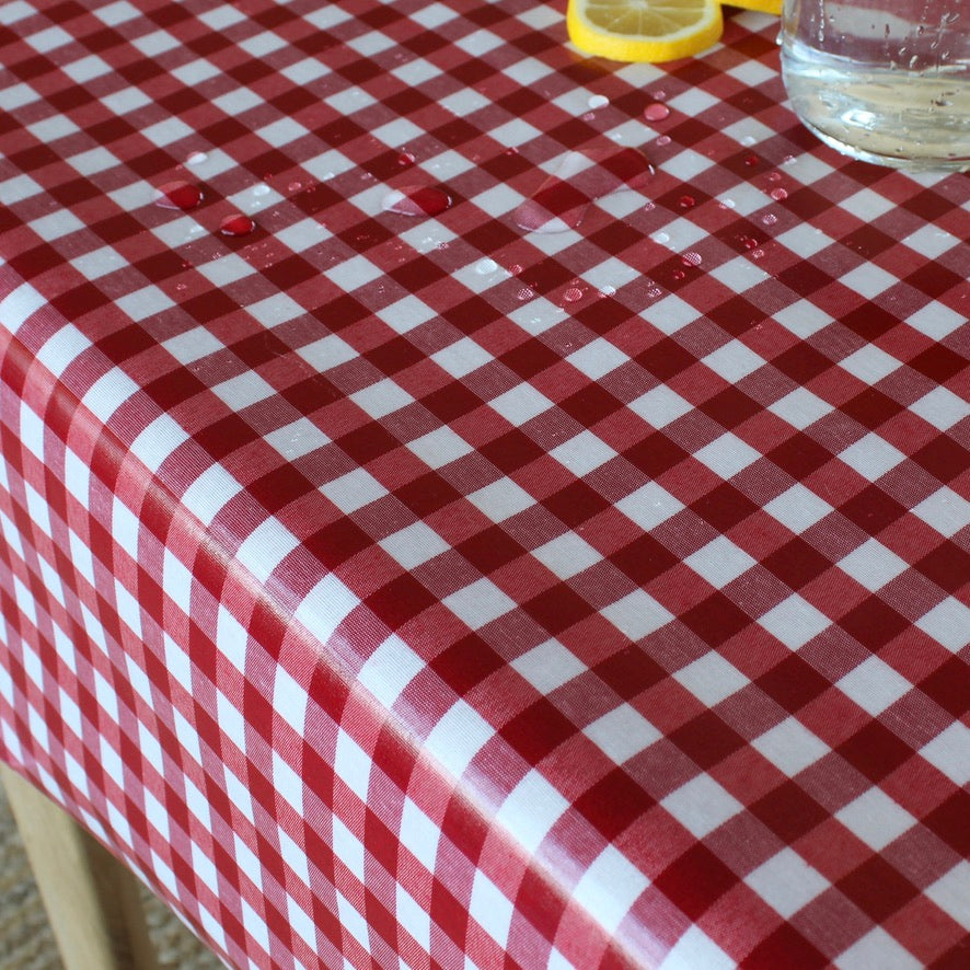 Red and white checkered tablecloth with a lemon and glass on a wooden surface.