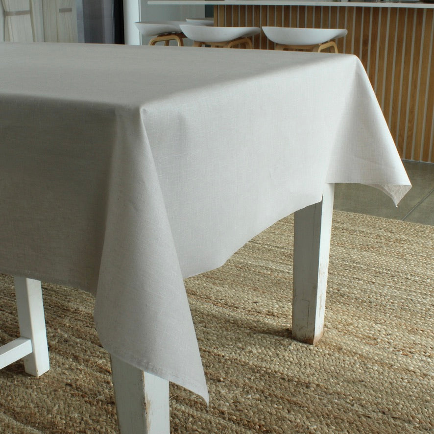 Grey tablecloth on a table with chairs in the background