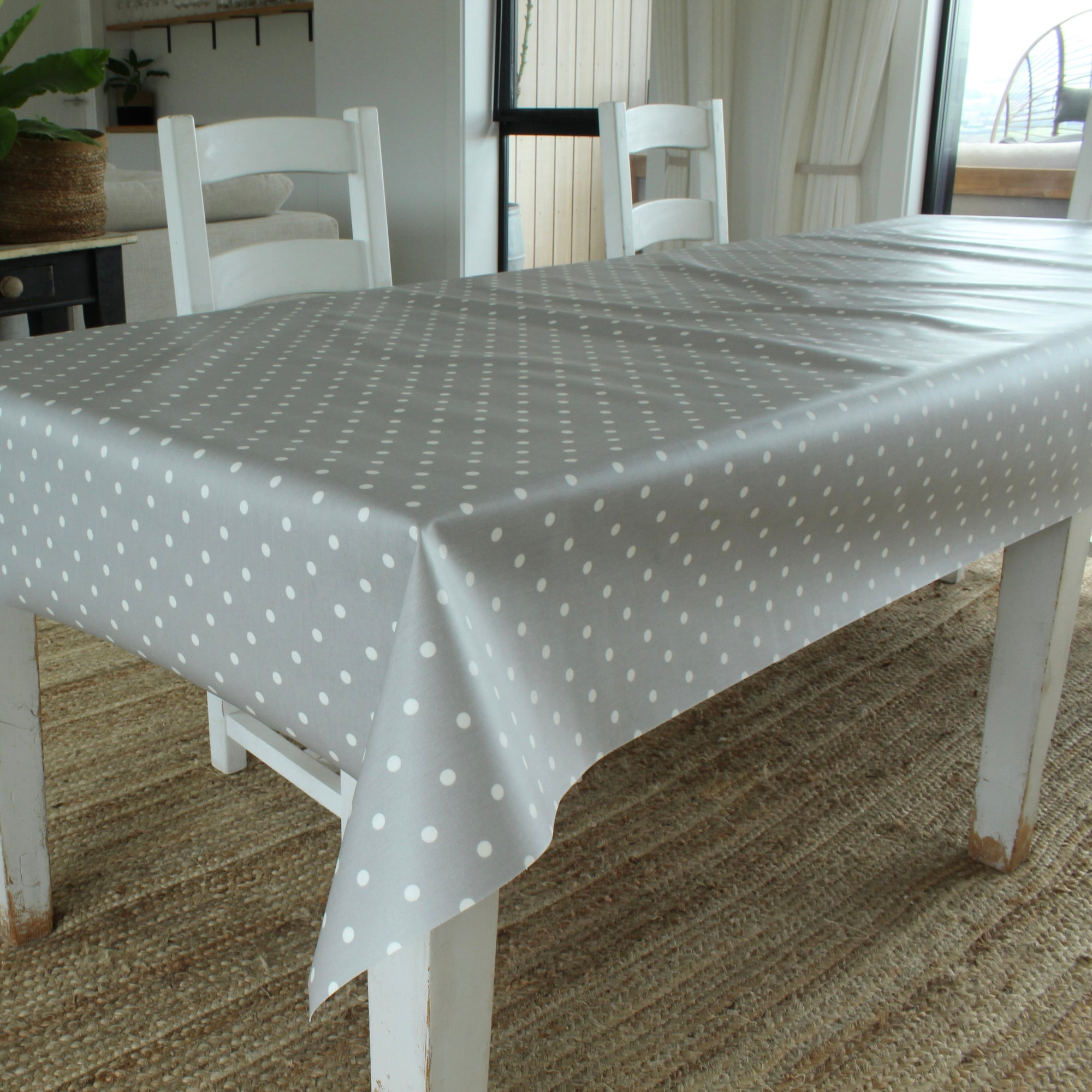 Dining table with a gray polka dot tablecloth in a room with chairs and decor.