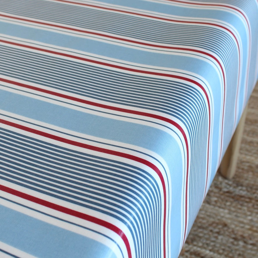 Close-up of a striped oilcloth with red, white, and blue lines on a light blue background.