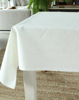 White tablecloth on a table in a room with a couch and plants.