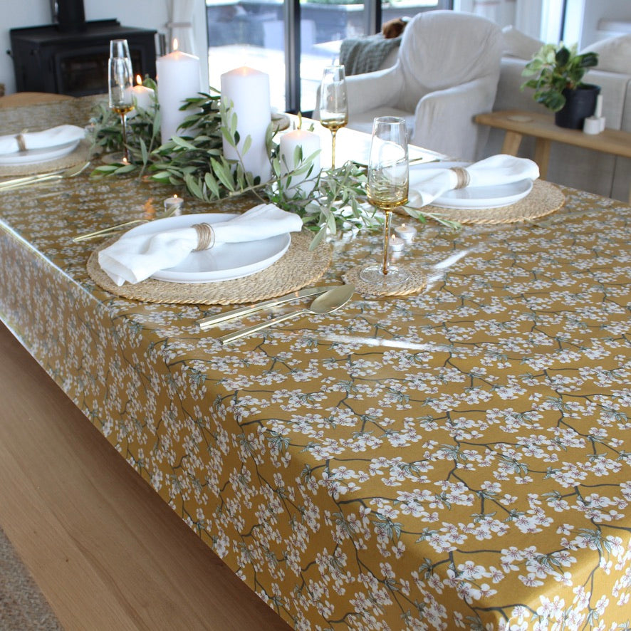 Dining table set with a floral tablecloth, plates, cutlery, and glasses.