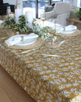 Dining table set with a floral tablecloth, plates, cutlery, and glasses.