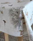 Tablecloth with nature-themed design featuring trees and animals on a wooden table.