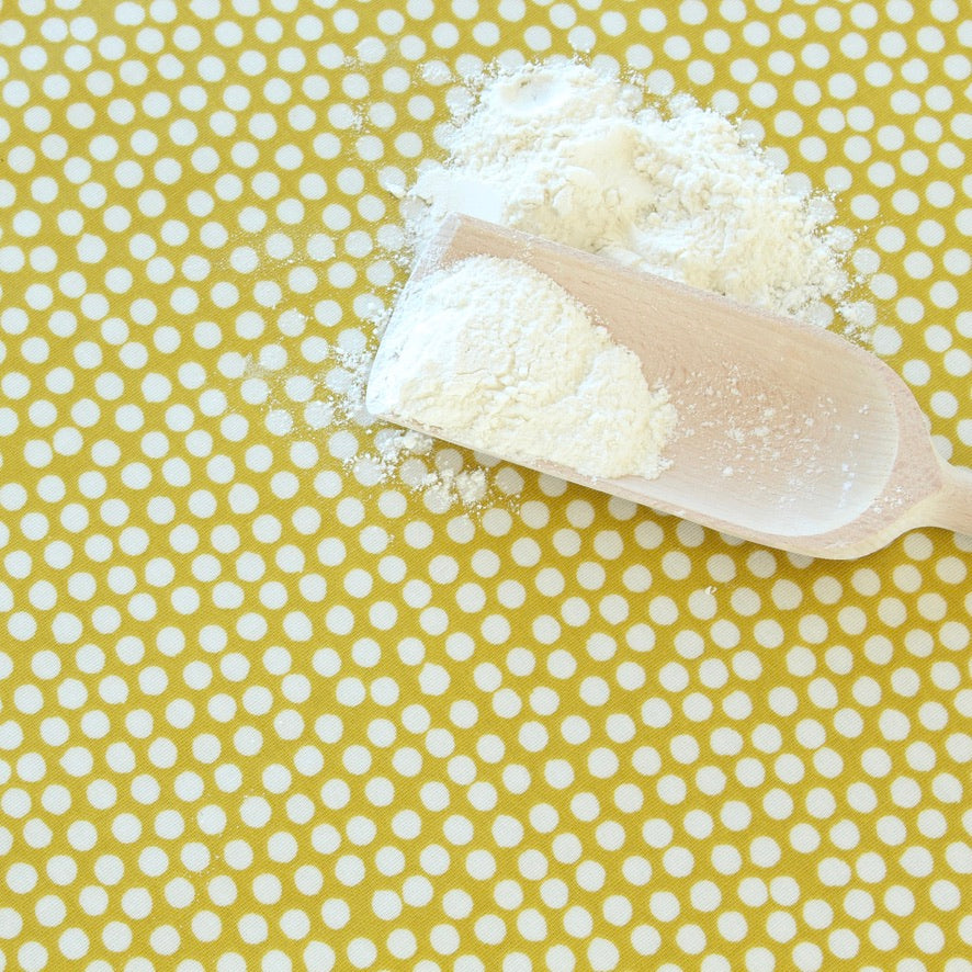 Spoonful of flour on a yellow oilcloth with white polka dots