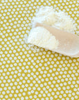 Spoonful of flour on a yellow oilcloth with white polka dots
