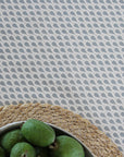 Green fruits in a bowl on a teardrop patterned oilcloth