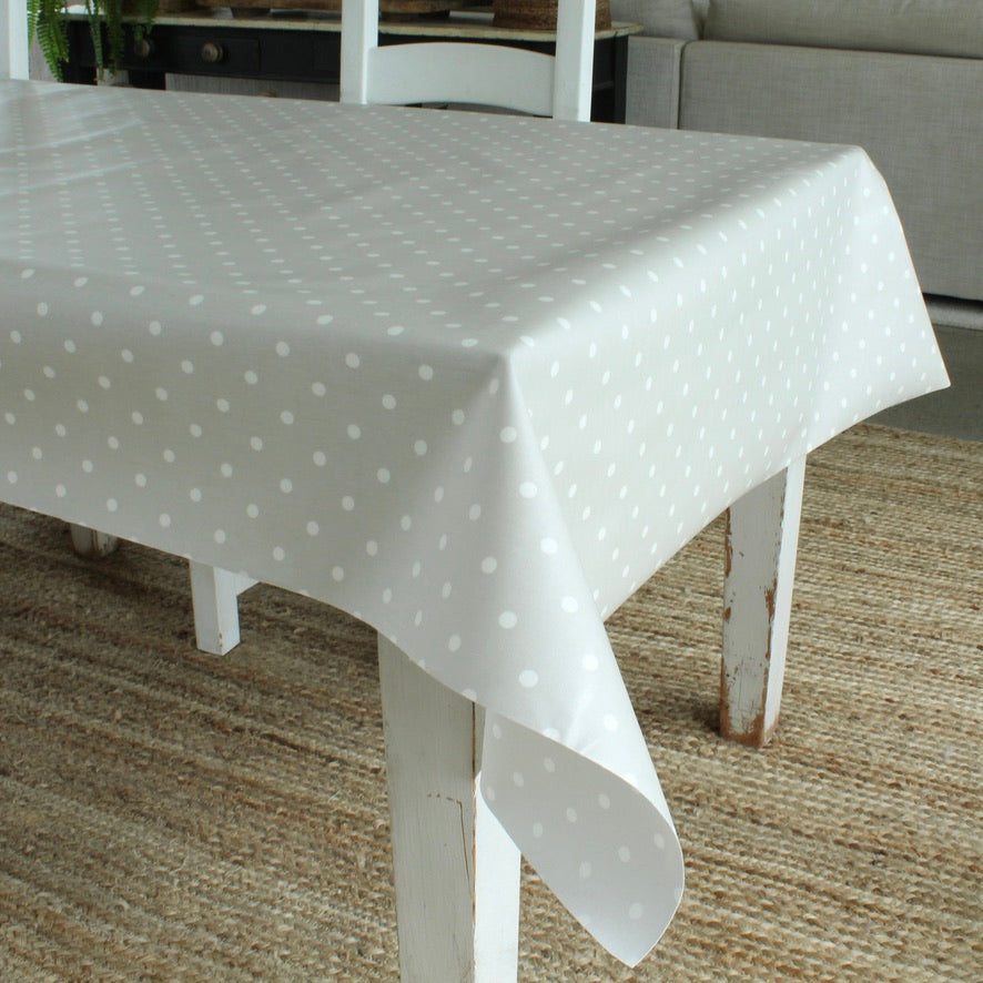 White polka dot tablecloth on a wooden table in a room with a couch and plant.