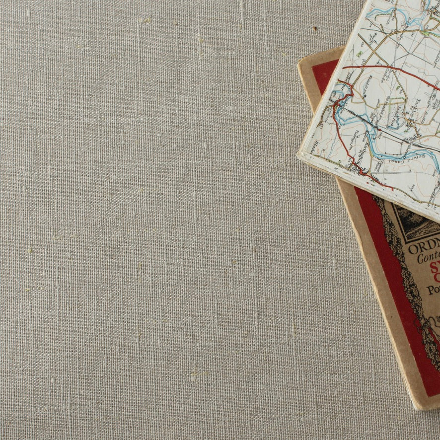 Stack of maps with a map on a beige linen tablecloth