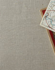 Stack of maps with a map on a beige linen tablecloth