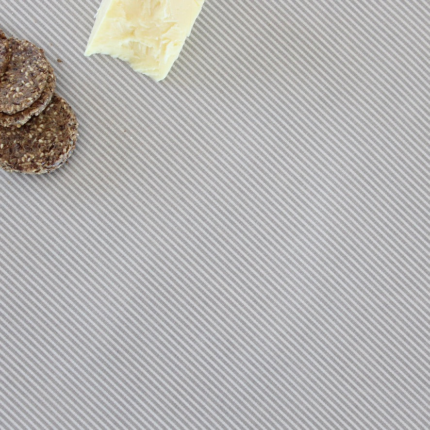 Crackers and a block of cheese on a striped tablecloth