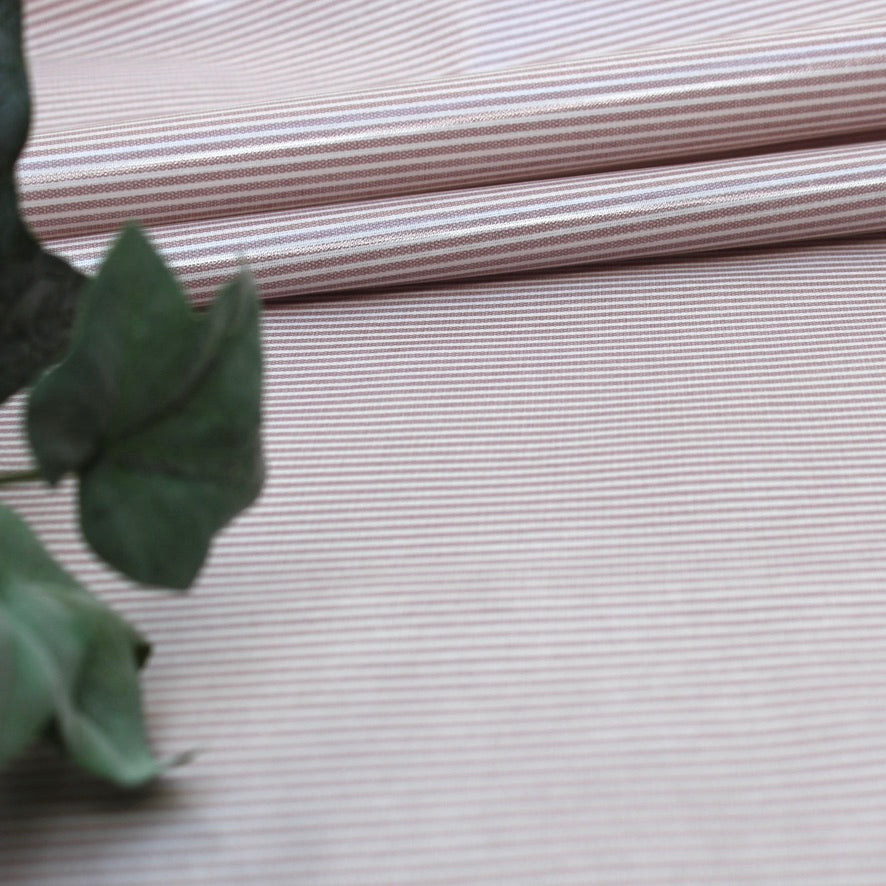 Close-up of striped oilcloth with a green leaf in the foreground