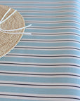 Close-up of a straw hat on a striped oilcloth with blue and white stripes.