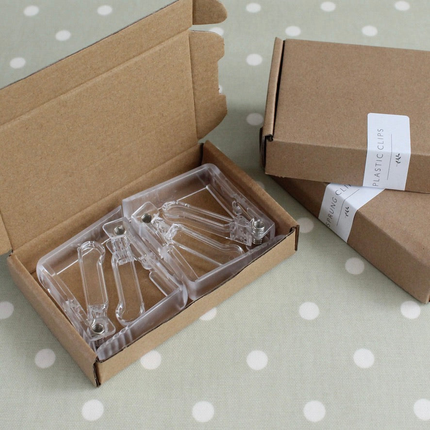 Clear plastic clips in a cardboard box on a polka dot surface